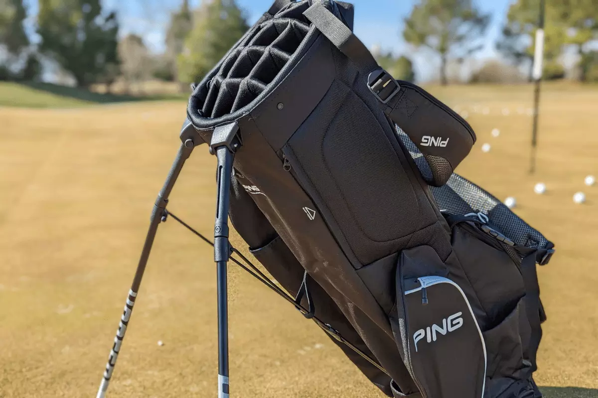 Black ping bag that has 14 full length dividers near a putting green with light blue on pocket