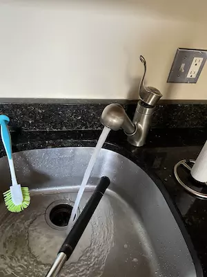 Bring the club to the rinse station (over a sink or outside) - Take the luke warm water and lightly coat the cleaned grip 