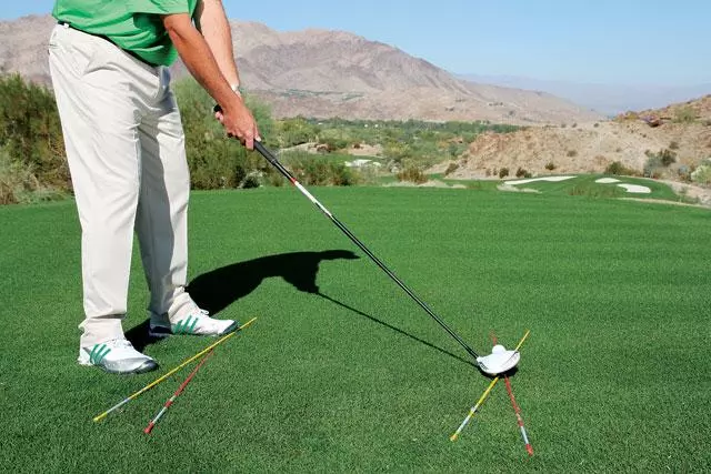<p>When you are at the range, on the course, or even just working on this at home, you need to make sure your setup is consistent. If the direction of your feet starts to change as you practice your backswing, you will have another factor that could throw off your swing path. </p>
<p>The alignment stick (or club) should be your guide in terms of where the path of the club should follow on the backswing. Therefore, your alignment stick should be pointing a bit further right than your target in the distance so that you can see your club following that line on your move backwards. </p>
Take a look at the image below - you could add a few more clubs to understand where your feet and club face need to point and the club path (see the yellow alignment sticks below).